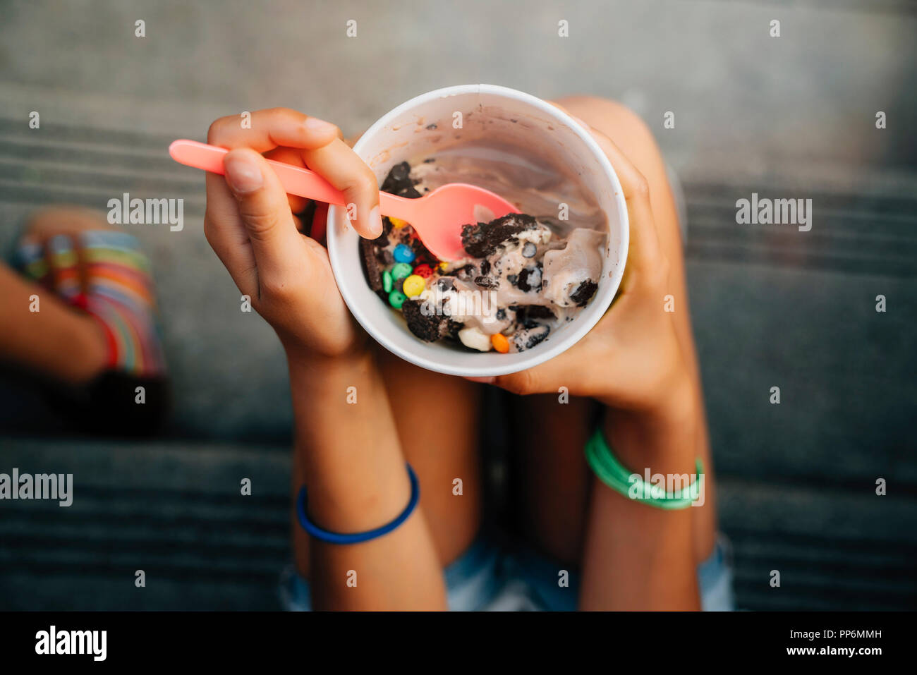 Hohen Winkel in der Nähe von Mädchen sitzen auf Schritte Eis essen Stockfoto