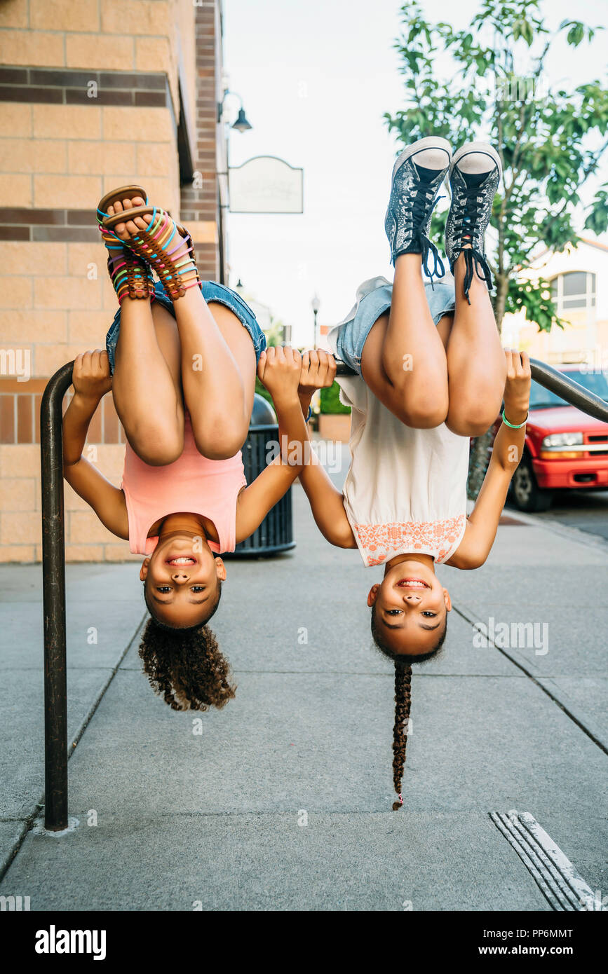 Glücklich lächelnde Mädchen hängen von Bike Rack bar auf Bürgersteig Stockfoto