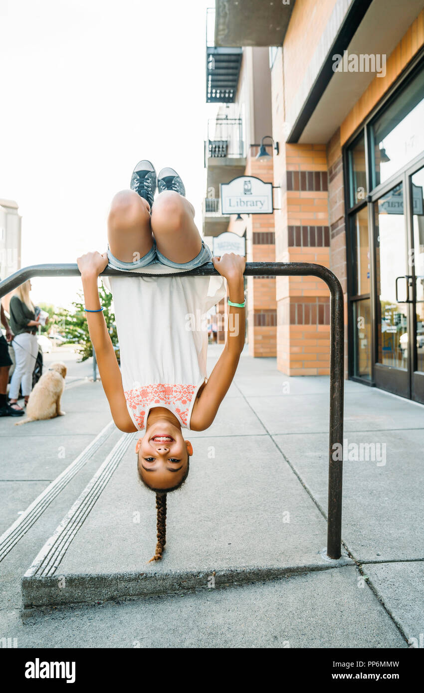 Glücklich lächelnde Mädchen hängen von Bike Rack bar auf Bürgersteig Stockfoto