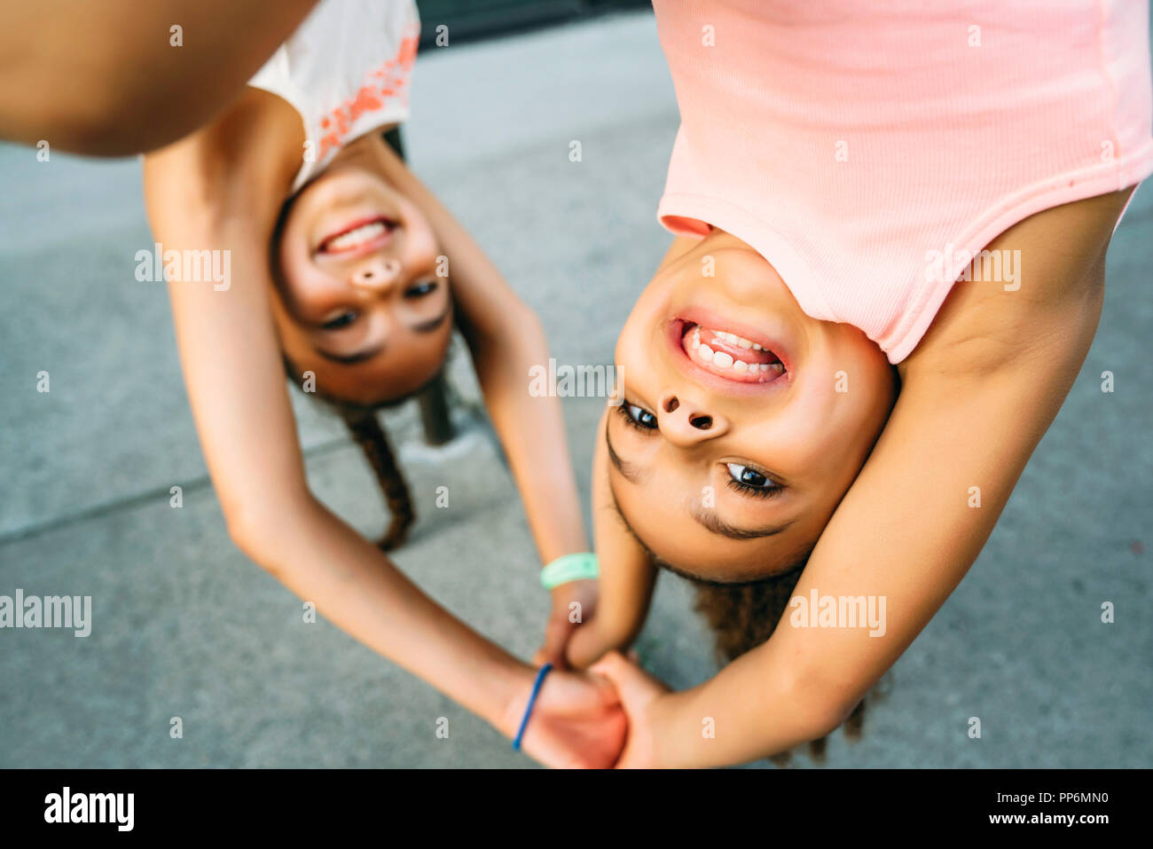 Glücklich lächelnde Mädchen hängen von Bike Rack bar auf Bürgersteig Stockfoto