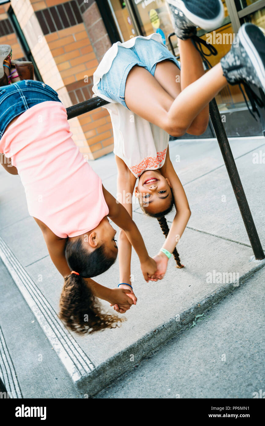 Glücklich lächelnde Mädchen hängen von Bike Rack bar auf Bürgersteig Stockfoto