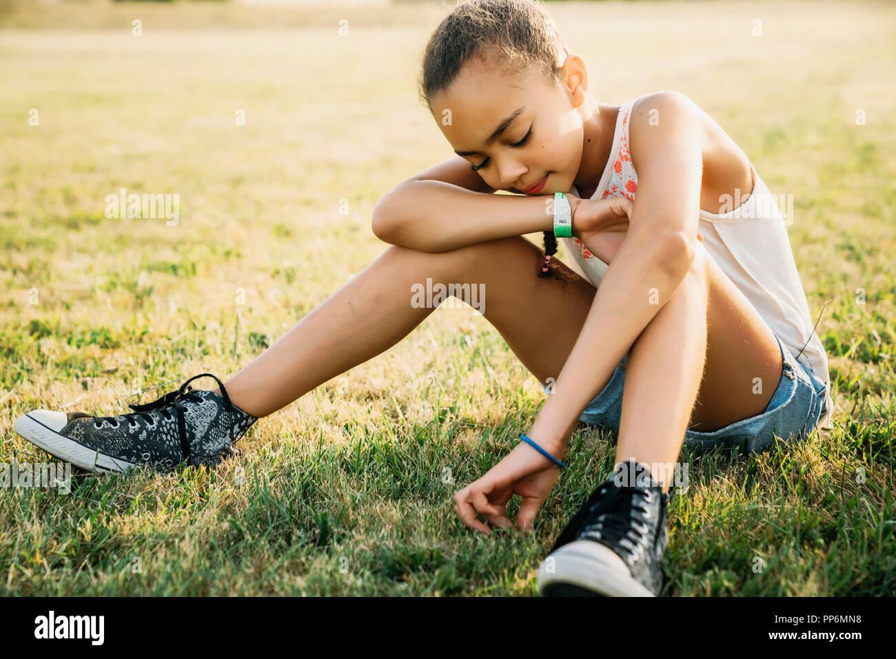 Mädchen sitzen im Bereich Kommissionierung Gras Stockfoto
