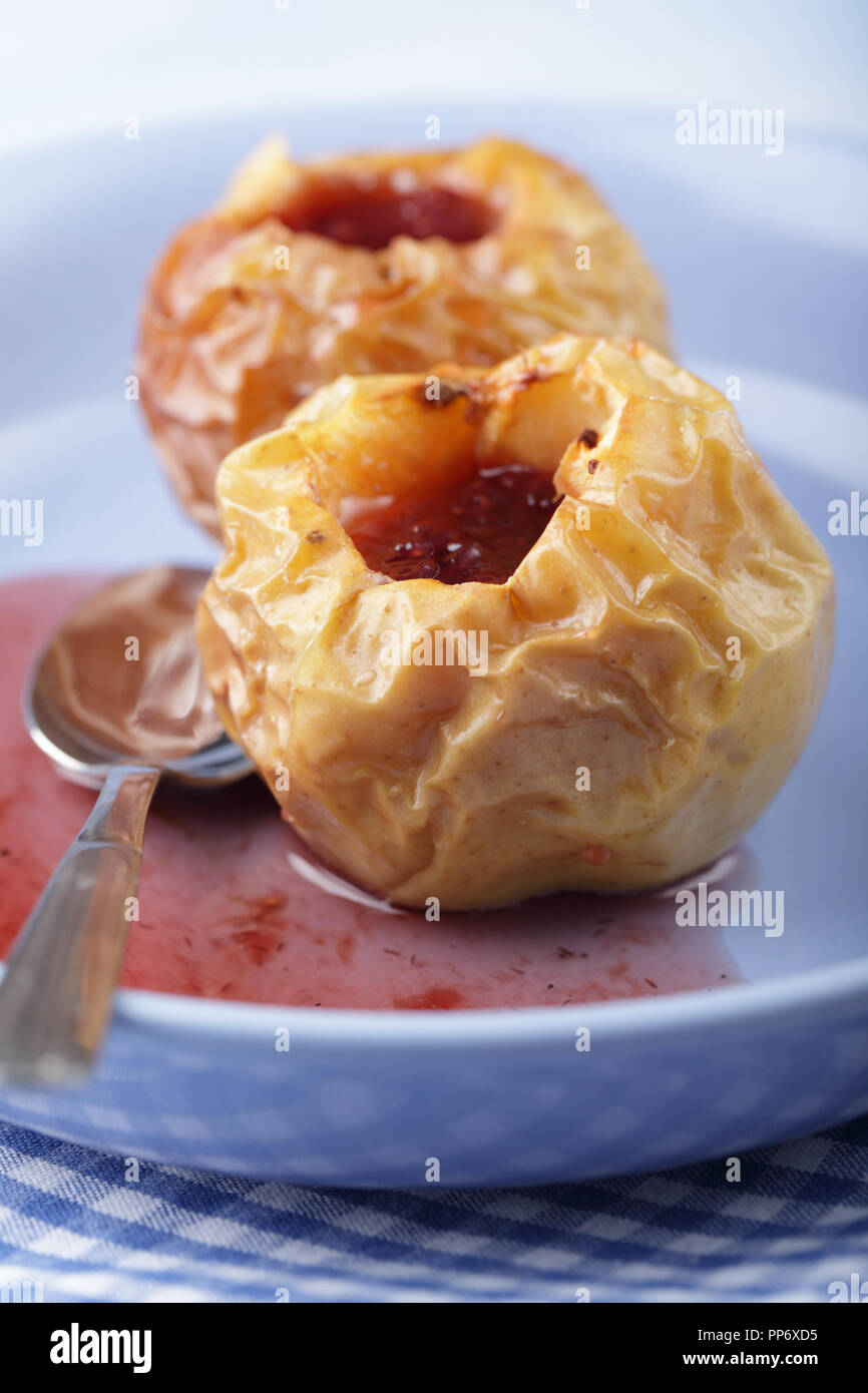 Gebackene Äpfel mit Erdbeermarmelade auf der blauen Platte Stockfoto