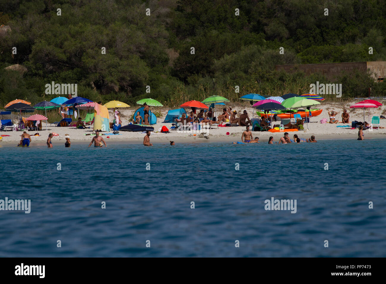 Sonnenanbeter und bunte Sonnenschirme am Strand. Sardinien. Italien Stockfoto