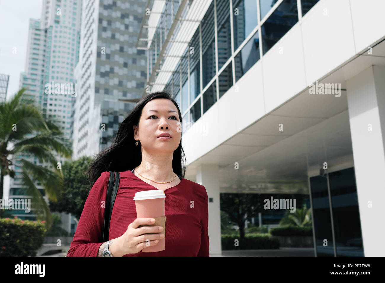 Gerne Chinesisch weiblicher Manager pendeln und Holding Kaffeetasse. Zuversichtlich asiatischen Geschäftsfrau im späten zu Fuß schnell zu Büro morgens. Stockfoto