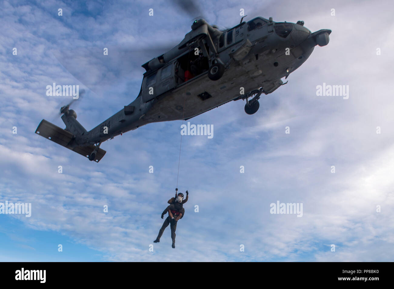 180922-N-WM 647-4101 philippinischen Meer (Sep. 22, 2018) Zwei Naval Aircrewmen (Hubschrauber), verwenden, um eine Rescue hoist in einem MH-60S Sea Hawk Hubschrauber zu erhalten, zum "goldenen Falken "Hubschrauber Meer Combat Squadron (HSC) 12, aus der Flight Deck der Arleigh-Burke-Klasse geführte Anti-raketen-Zerstörer USS Benfold (DDG65) während einer Suche und Rettung übung, als Teil der Valiant Shield 2018 zugeordnet. Valiant Shield ist ein nur in den USA, zweijährige Feld Training übung (Ftx) mit einem Fokus auf Integration der gemeinsame Ausbildung in ein Blau - Wasser Umwelt unter den US-Streitkräften. Diese Ausbildung ermöglicht reale Kenntnisse in sust Stockfoto