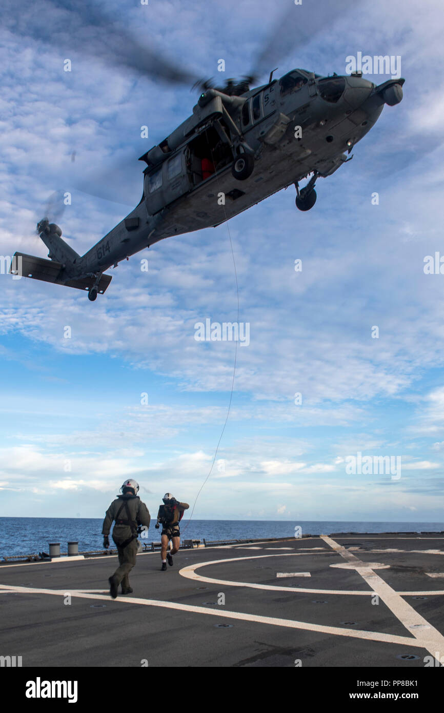 180922-N-WM 647-4049 philippinischen Meer (Sep. 22, 2018) Naval Aircrewman (Hubschrauber) 3. Klasse Jose Mejia, rechts, von Houston, Ansätze Naval Aircrewman (Hubschrauber) 2. Klasse Paul Bush von Mukilteo, Washington, auf dem Flugdeck der Arleigh-Burke-Klasse geführte Anti-raketen-Zerstörer USS Benfold (DDG65) mit einem rescue Hoist von einem MH-60S Sea Hawk Hubschrauber, zum "goldenen Falken "Hubschrauber Meer Combat Squadron (HSC) 12, bei der Suche und Rettung, als Teil der Valiant Shield 2018 zugeordnet. Valiant Shield ist ein nur in den USA, zweijährige Feld Training übung (Ftx) mit einem Fokus auf Integration von Stockfoto