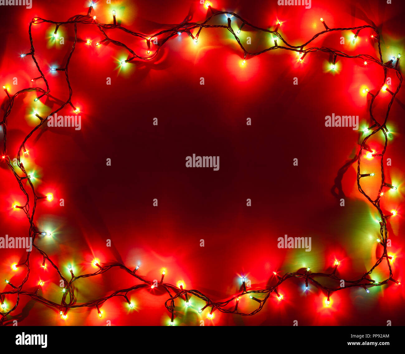 Weihnachtsbeleuchtung in verschiedenen Farben Rahmen auf rotem Hintergrund Stockfoto