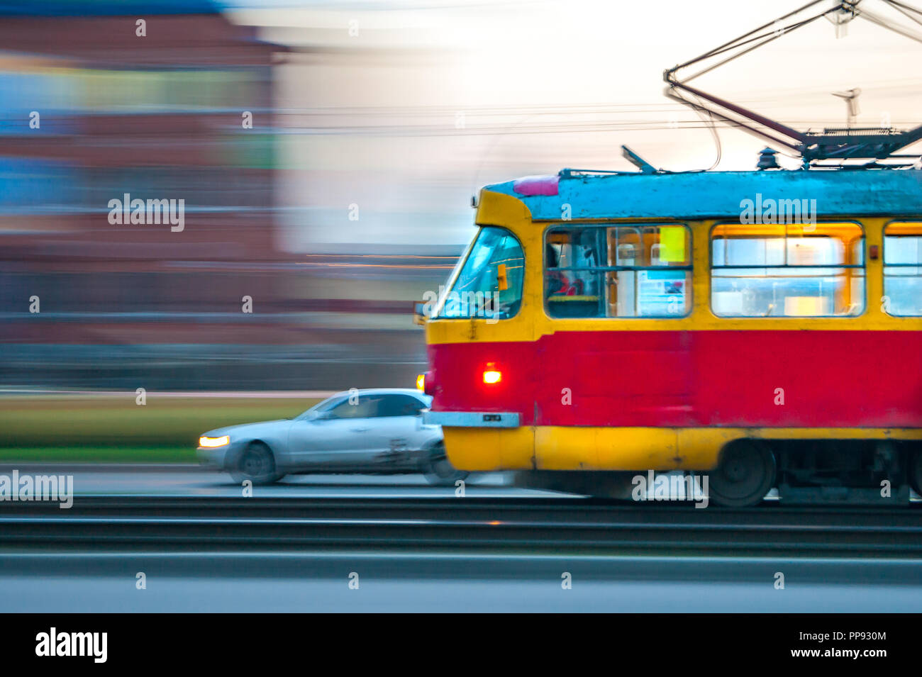 Schnell beweglichen roten und gelben Straßenbahn in der Stadt mit Licht auf, Panning verschwommen Effekt Stockfoto