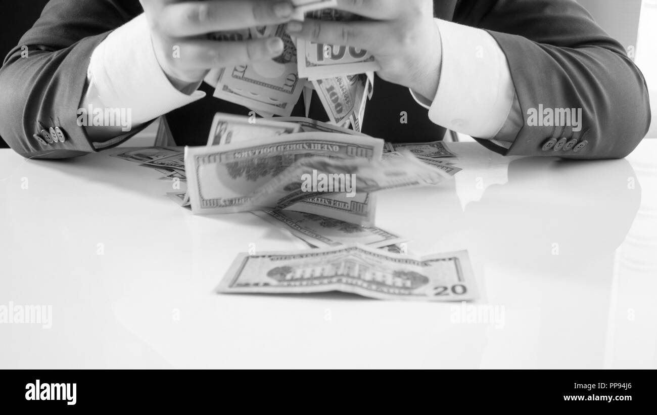Detailansicht schwarz-weiß Bild von gierigen Unternehmer greifen und werfen große Stapel von Geld Stockfoto