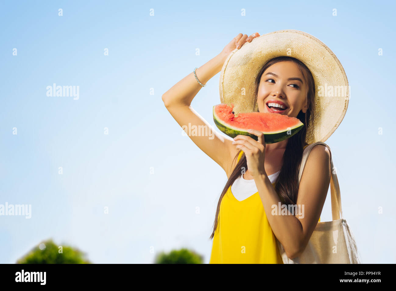 Freudige positive asiatische Frau berühren ihren Hut Stockfoto Freudige positive asiatische Frau berühren ihren Hut Stockfoto