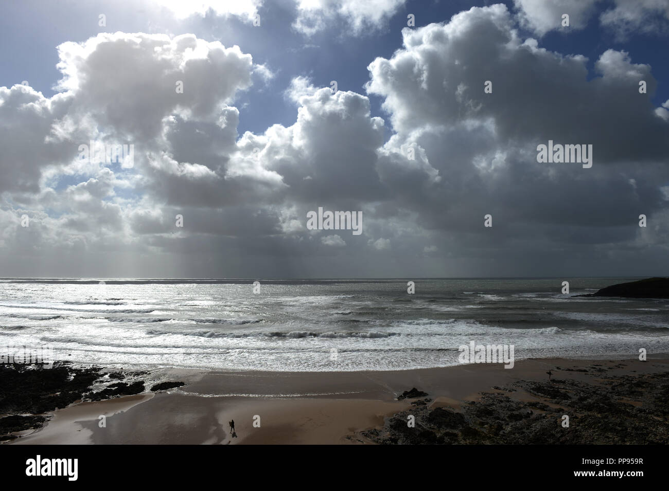 Dusche Wolken über dem Meer und Surfen übersäten Strand bei Ebbe Stockfoto