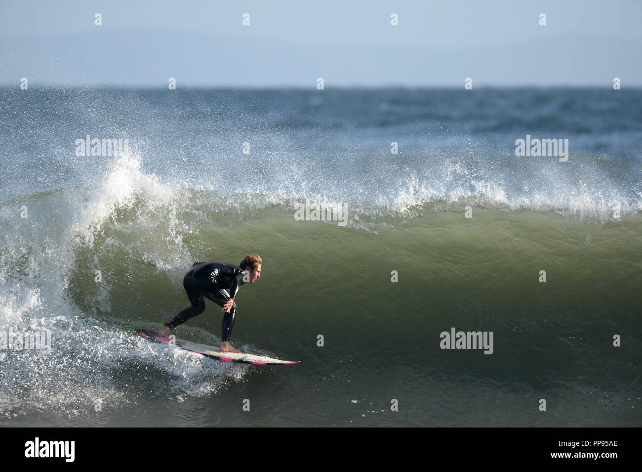 Ein surfer Winkel sein Brett nach unten eine grüne Wand aus Wasser stopfte in für ein Rohr Stockfoto