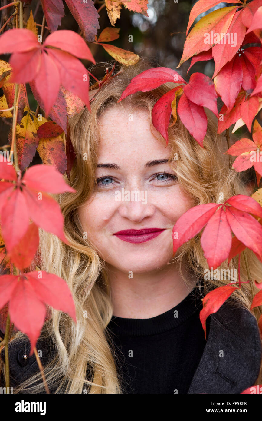 Im Herbst hapiness der blonde junge Frau, die in der Nähe von Laub Trauben" Stockfoto