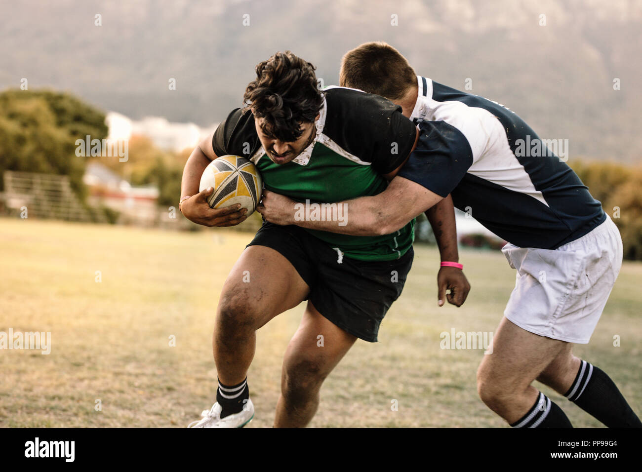 Professionelle Rugby-Spieler, die sich während des Spiels um den Ball bemühen. rugbyspieler mit Ball wird vom anderen Spieler am Boden blockiert. Stockfoto