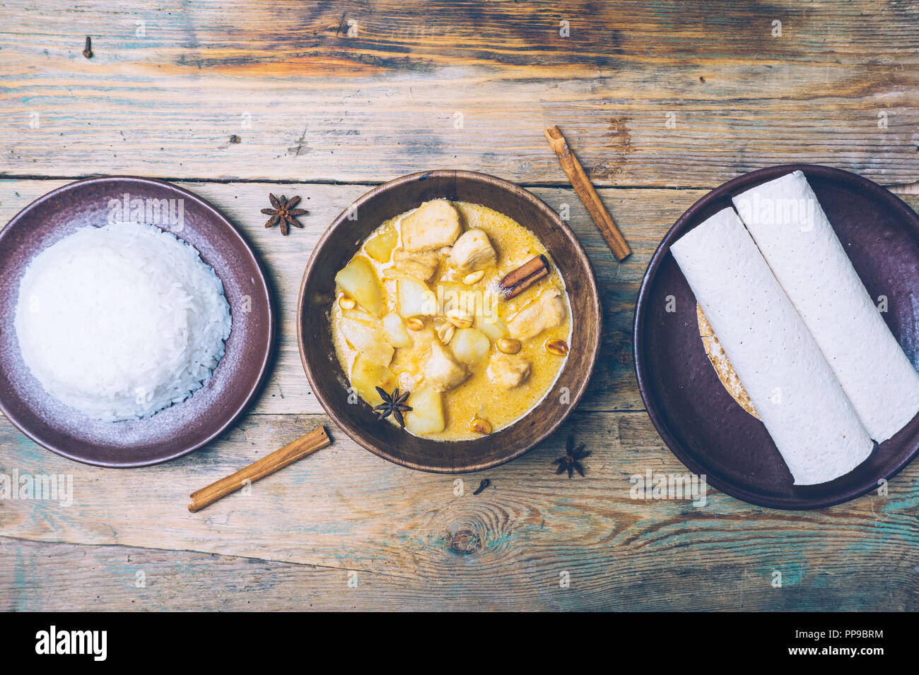 Thai Massaman Curry (Chicken Curry) mit Zimtstangen und Flugzeug riсe auf Holz- Hintergrund. Kokosmilch Curry. Stockfoto