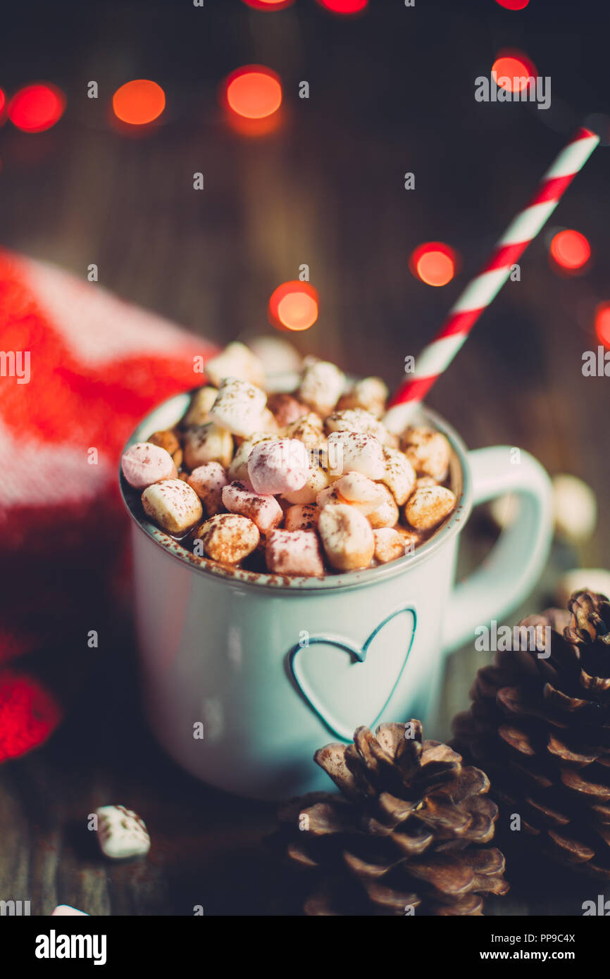 Weihnachten heiße Schokolade mit Marshmallows auf einem rustikalen Holztisch mit kiefernzapfen, rote Wolle Socken und roten Ampeln. Selektiver Fokus Stockfoto