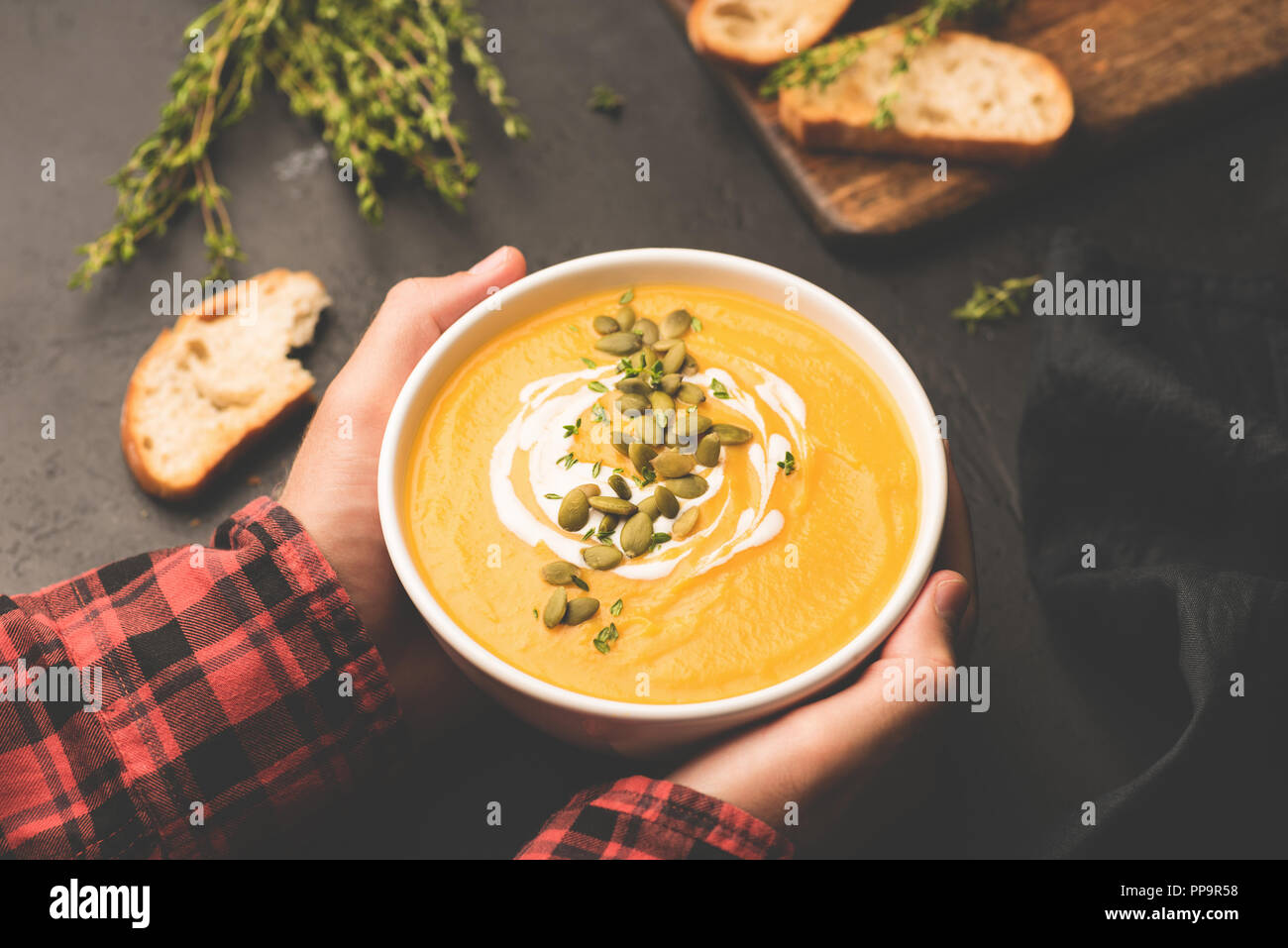 Person, die Schüssel mit warmem Kürbis Suppe in die Hände. Komfort Essen, Herbst essen Konzept Stockfoto