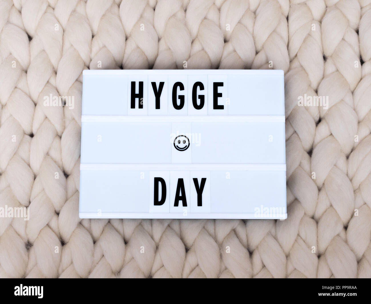 HYGGE TAG Wort auf Lightbox auf Stricken Hintergrund. Gemütliche compozition. Stricken Hintergrund. Stockfoto