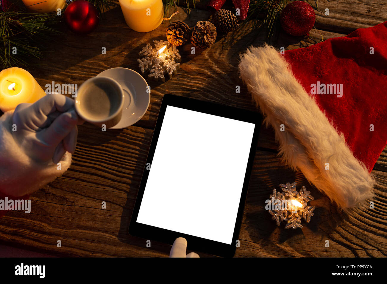 Santa Claus Hände mit Kaffee und Tablet Stockfoto