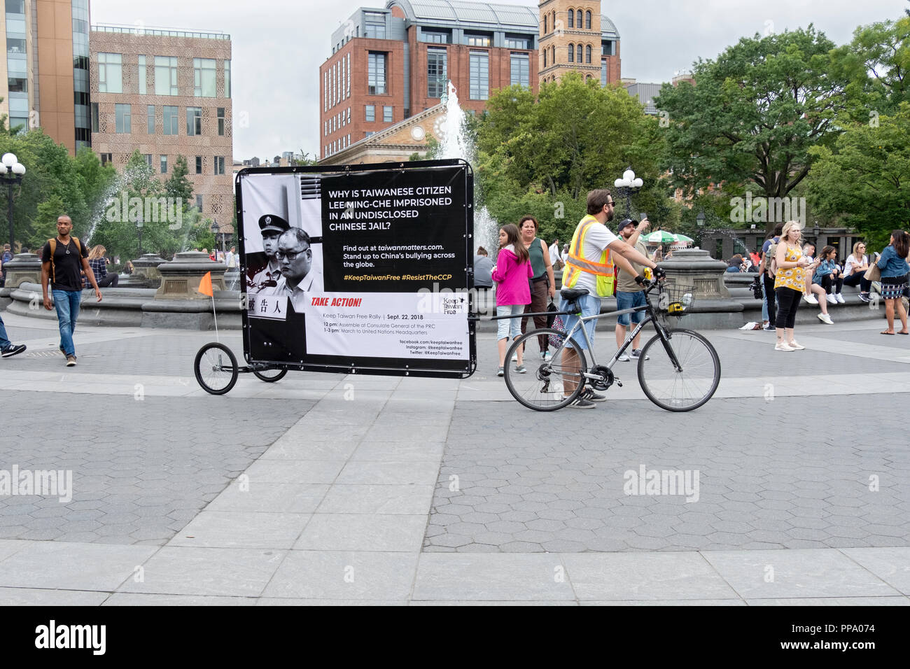 Ein Mann in Washington Square Park mit dem ungewöhnlichen Job zeigen Plakate von einem Fahrrad. Greenwich Village, New York 2018 Stockfoto