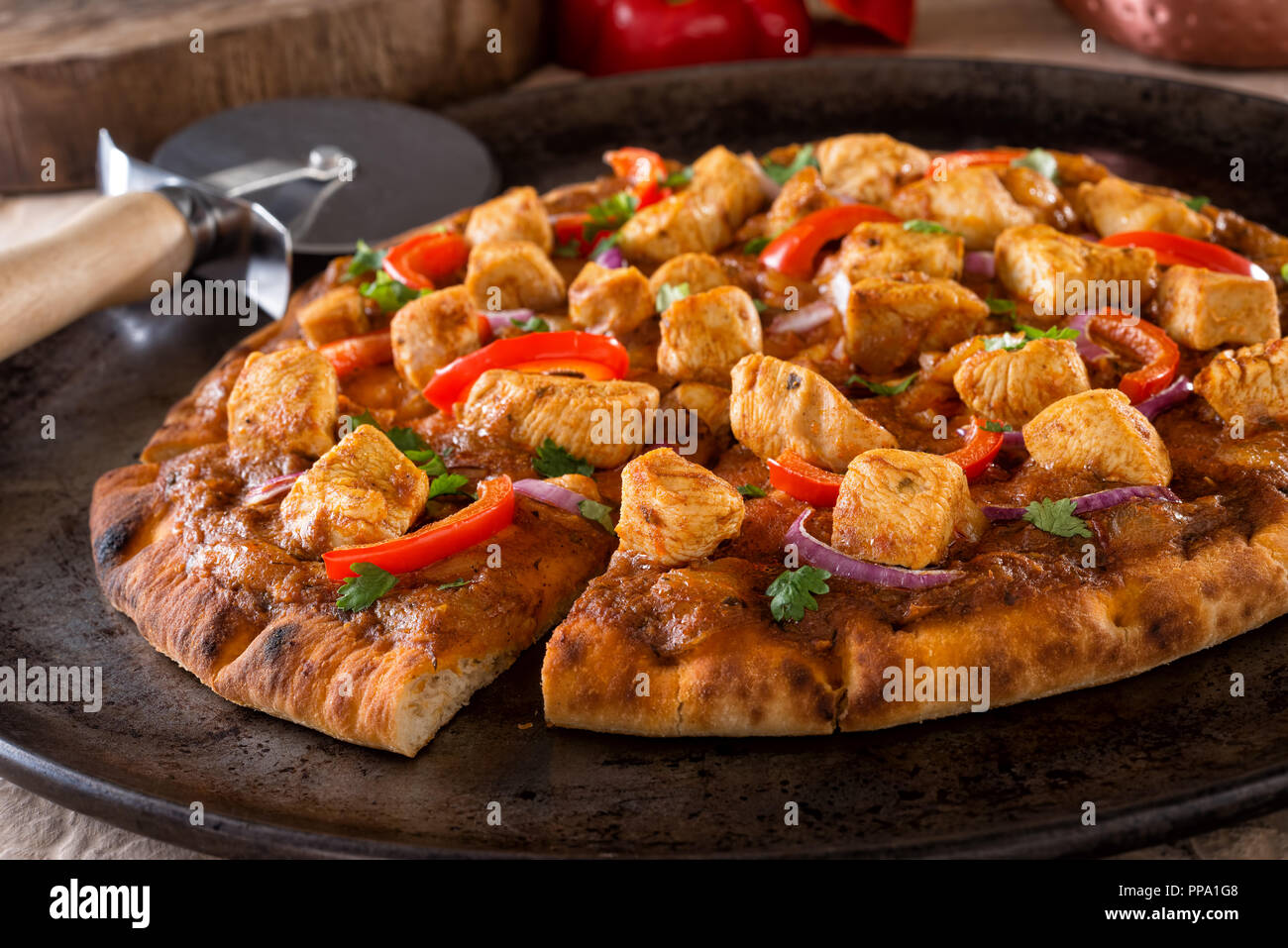 Eine köstliche Butter Chicken Pizza mit Paprika, rote Zwiebeln und Koriander. Stockfoto