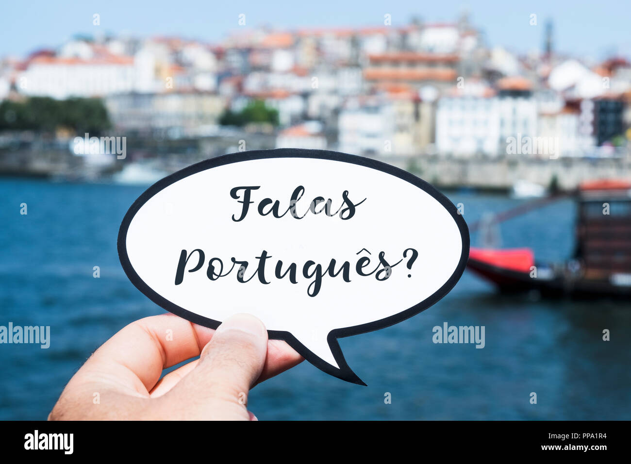 Die Hand eines jungen kaukasischen Mann hält eine Sprechblase mit der Frage portugues Falas, sie Portugiesisch sprechen? In Portugiesisch, in Porto geschrieben, Stockfoto