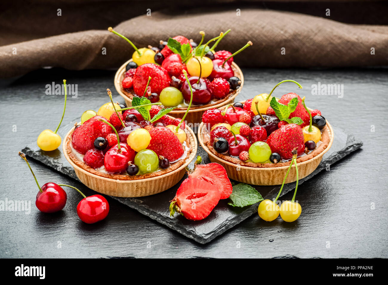 Berry Törtchen mit Blaubeeren, Himbeeren, Kiwi, Erdbeeren, Mandelflocken in Puderzucker. Stockfoto