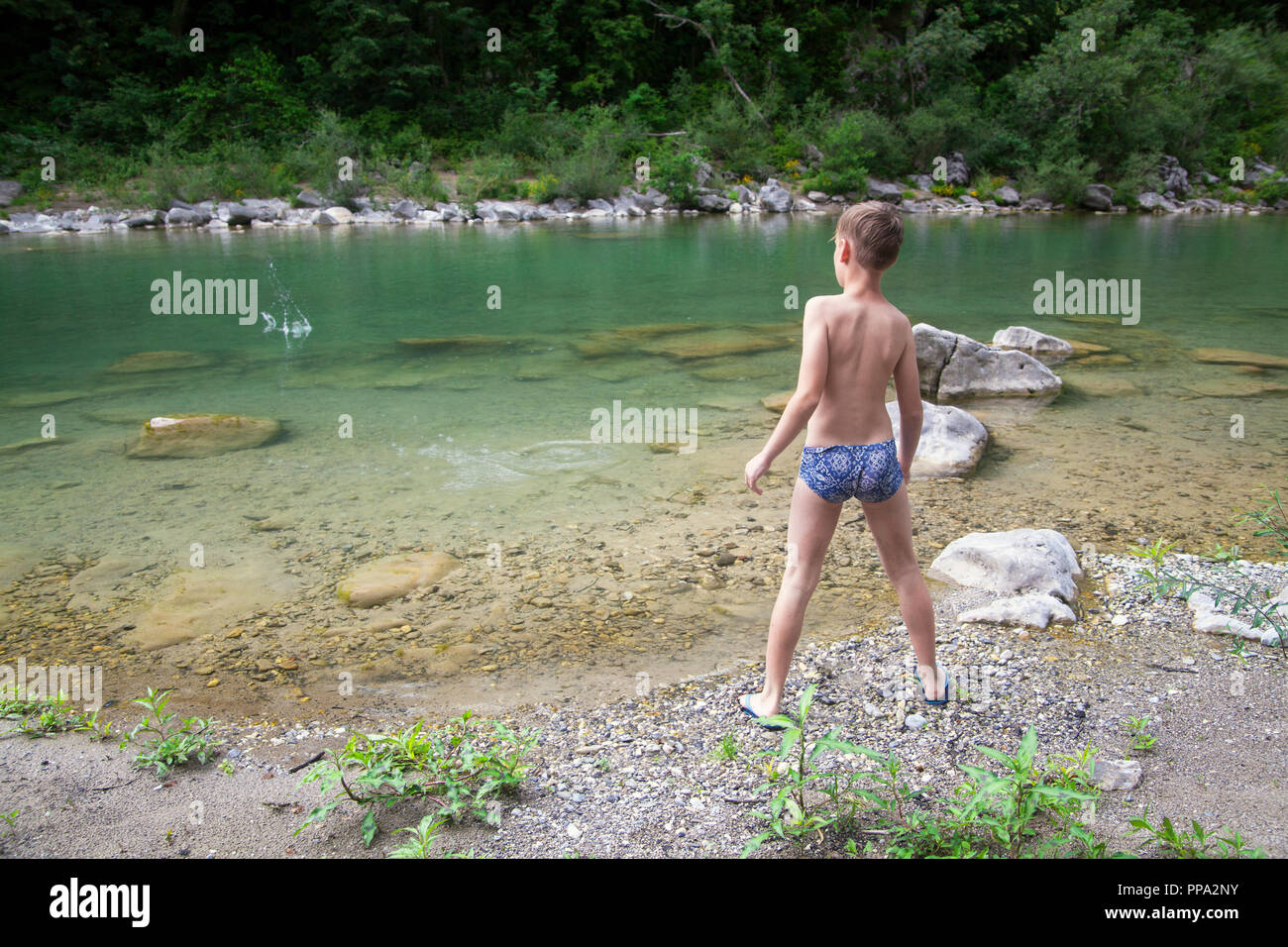 Junge warfen Steine im Fluss Stockfoto