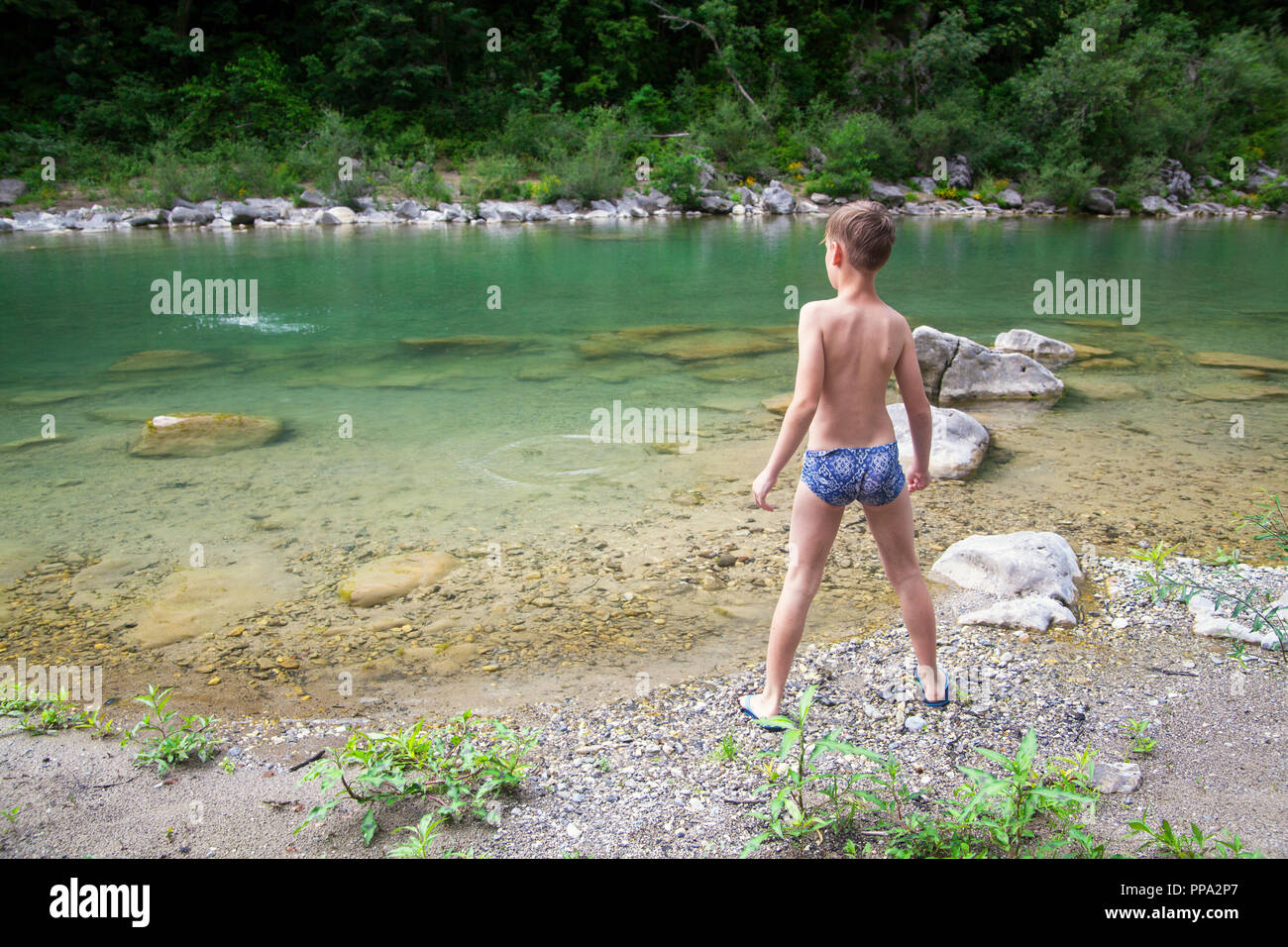 Junge warfen Steine im Fluss Stockfoto