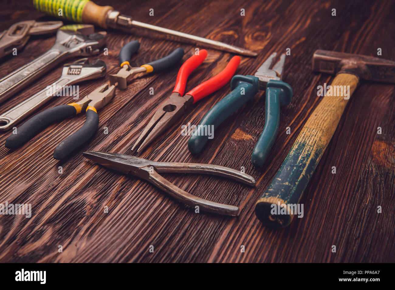 Verschiedene Werkzeuge auf einem Holztisch - ein Hammer, Seitenschneider, Zange, Meißel und Schlüssel Stockfoto