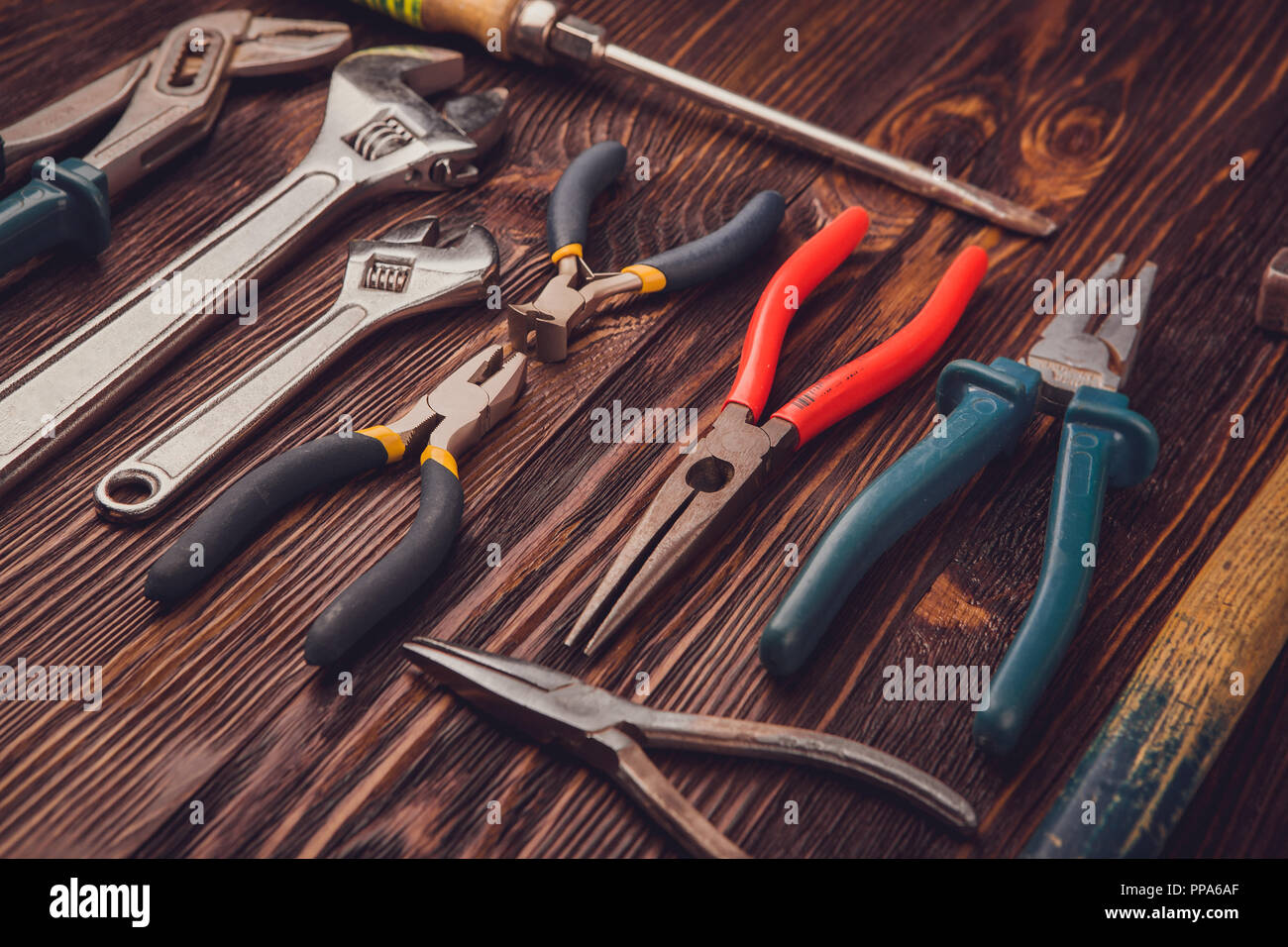 Verschiedene Werkzeuge auf einem Holztisch - ein Hammer, Seitenschneider, Zange, Meißel und Schlüssel Stockfoto