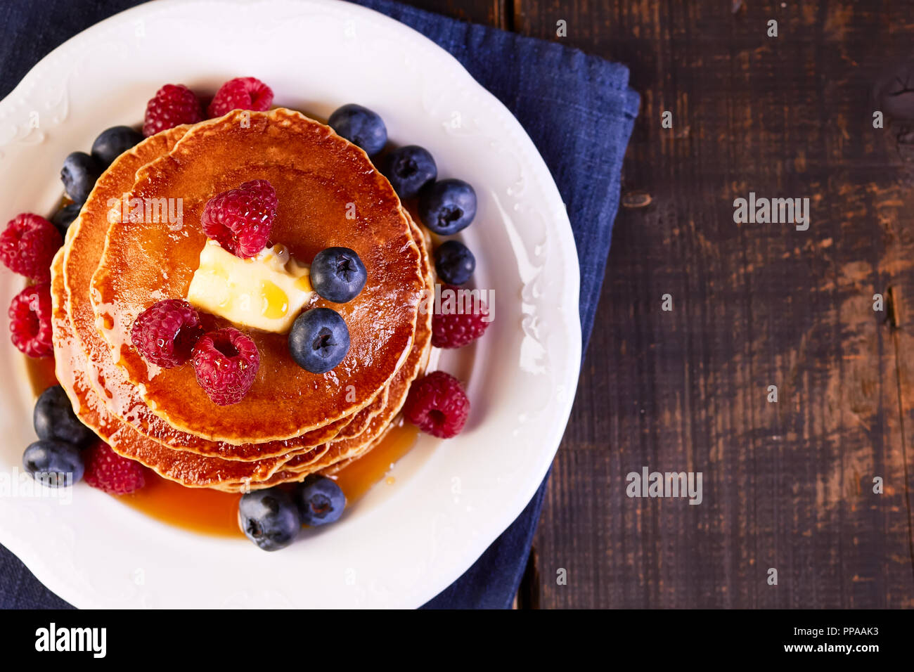 Pfannkuchen mit frischen Beeren Ahornsirup und Butter auf hölzernen Tisch Stockfoto