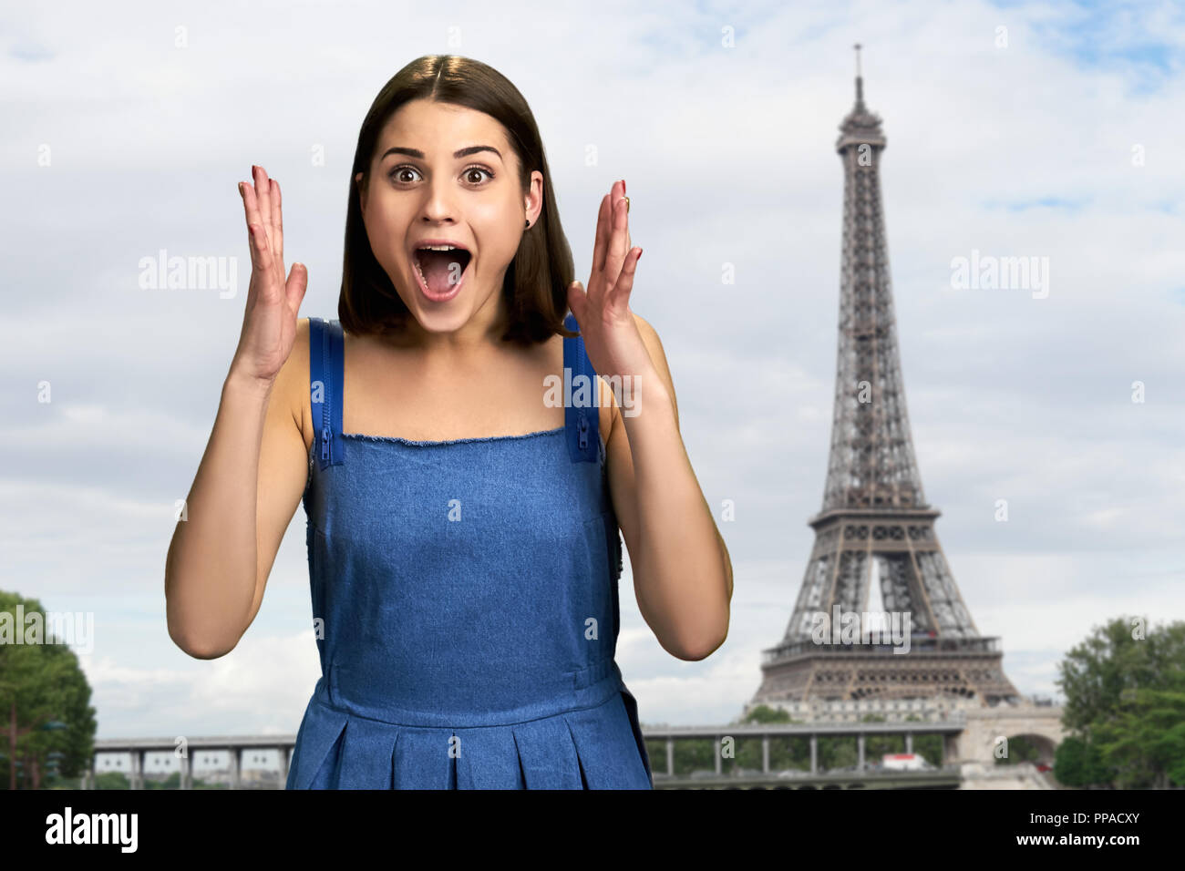 Aufgeregt Mädchen auf Eiffelturm Hintergrund. Gerne weibliche Touristen auf Reisen Urlaub jubel Freude mit erhobenen Armen. Menschlichen Ausdrucksformen der Aufregung. Stockfoto