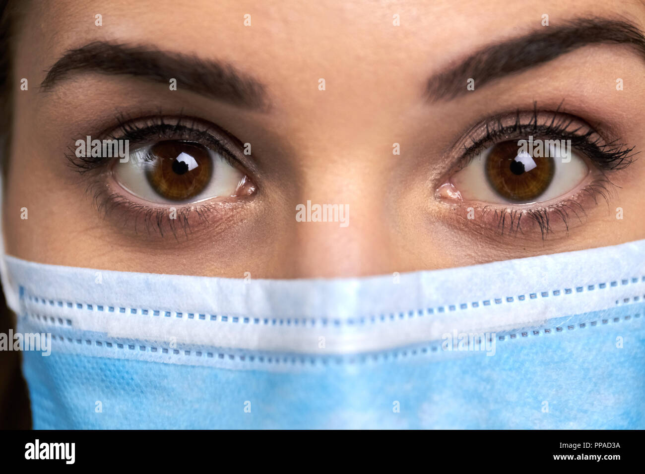 Schließen bis weit geöffneten Augen des Arztes. Ärztin in Schutzmaske mit überraschten Augen schließen. Menschlichen Ausdruck der Überraschung. Hazel Farbe Augen. Stockfoto