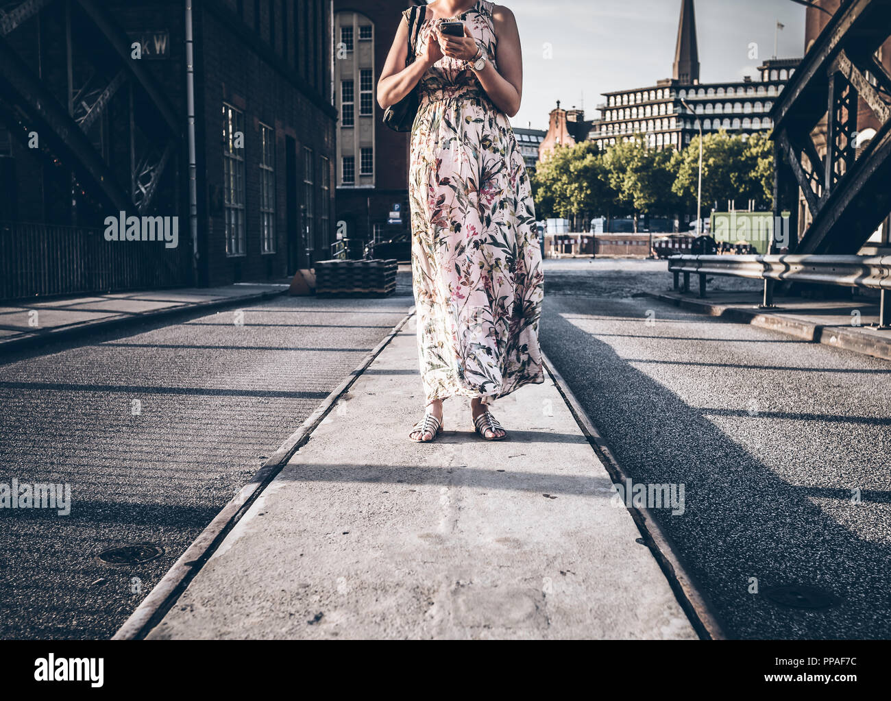 Frau im Sommerkleid stehen auf der Straße mit Hilfe von Phone Stockfoto