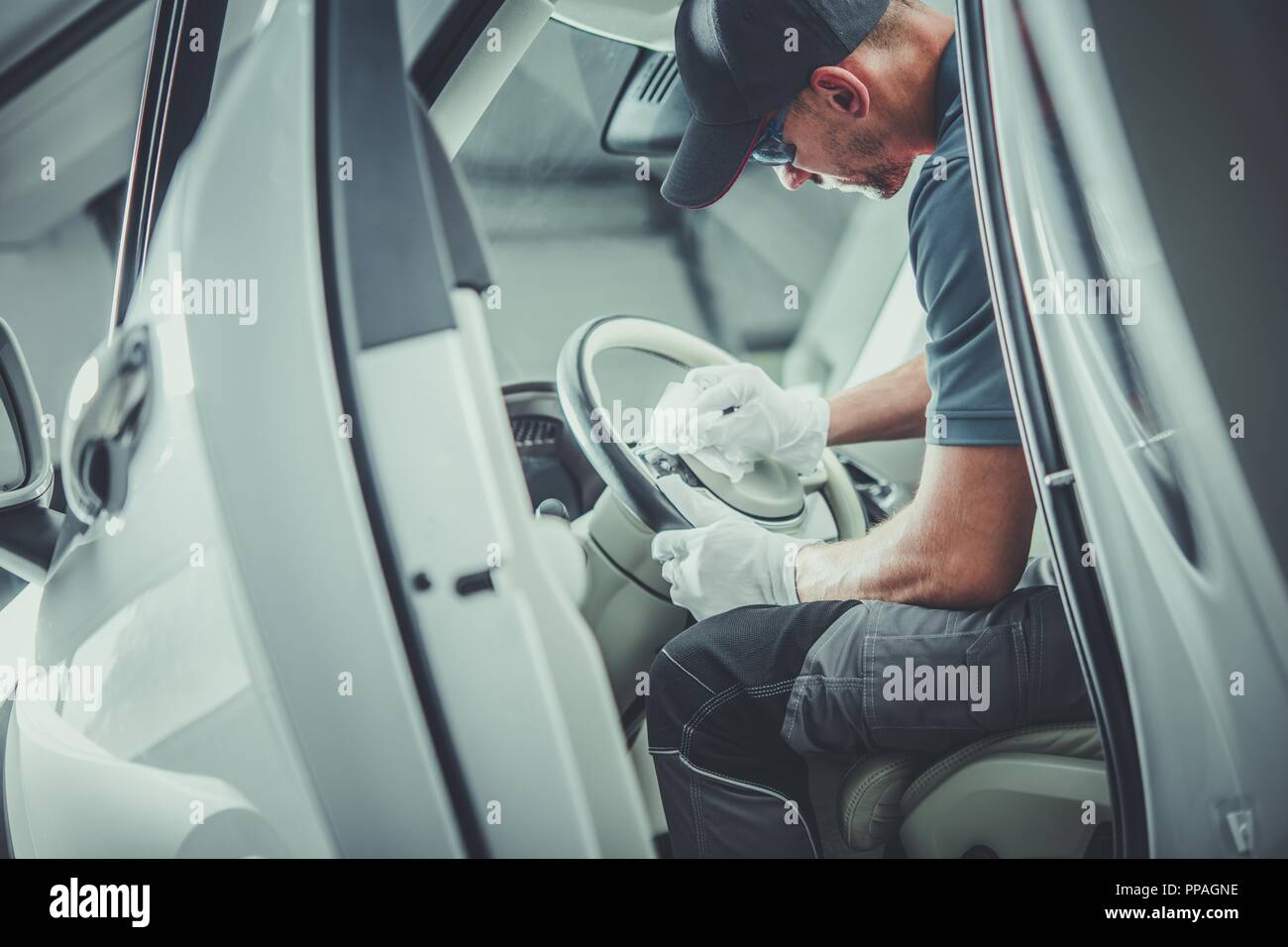 Von Autoteilen sauberer. Kaukasische Automotive Händler Arbeiter in seinem 30s Vorbereitung des Fahrzeugs zum Verkauf. Detaillierte Fahrzeuginnenraum reinigen. Stockfoto