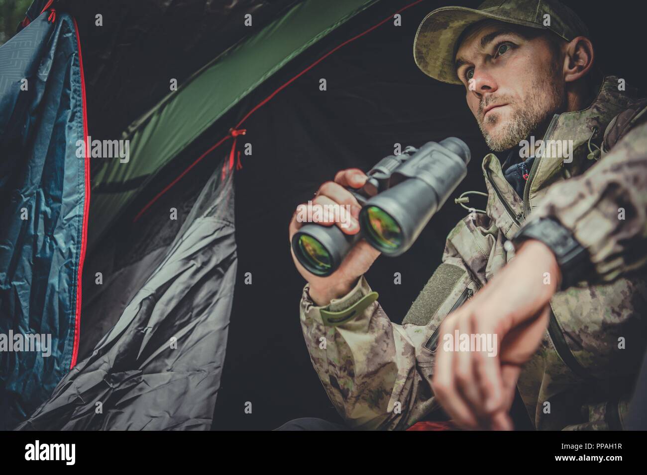 Kaukasische Hunter Spotting Wildlife aus seinem Zelt in abgelegenen Ort. Stockfoto