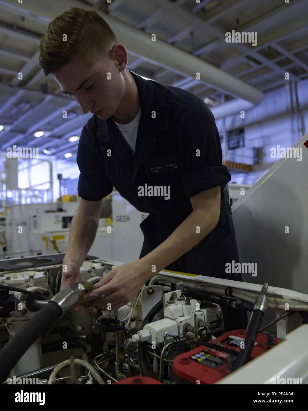Ozean (Aug. 23, 2018) Aviation Support Equipment Techniker Airman Easton Finger führt einen neuen Motor auf einem Spotting dolly im Hangar Bucht der Nimitz-Klasse Flugzeugträger USS Abraham Lincoln (CVN 72). Abraham Lincoln wird derzeit die Durchführung von Carrier Qualifikationen. Stockfoto