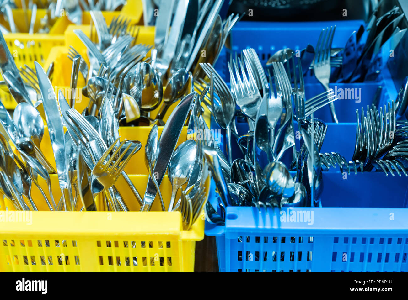 Besteck und Geschirr in bunten palstic ocntainer in einem industriellen Restaurant Küche sauber und frisch aus der Spülmaschine Stockfoto