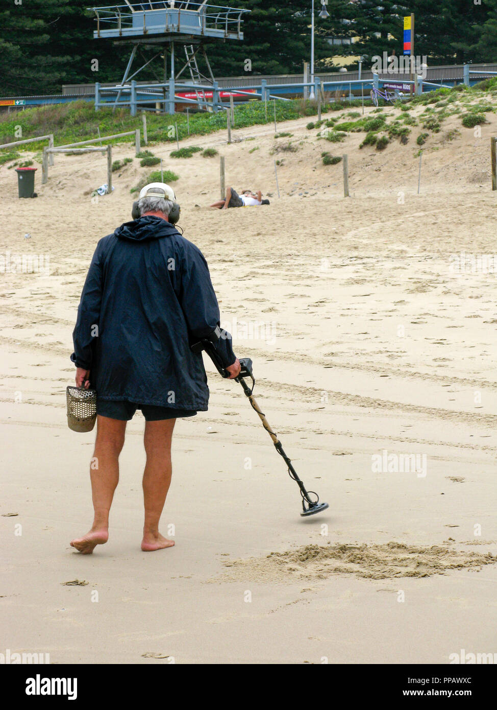 Mann mit Metalldetektor t einen Strand außerhalb von Sydney Australien, auf der Suche nach versteckten Gegenständen aus Metall Stockfoto