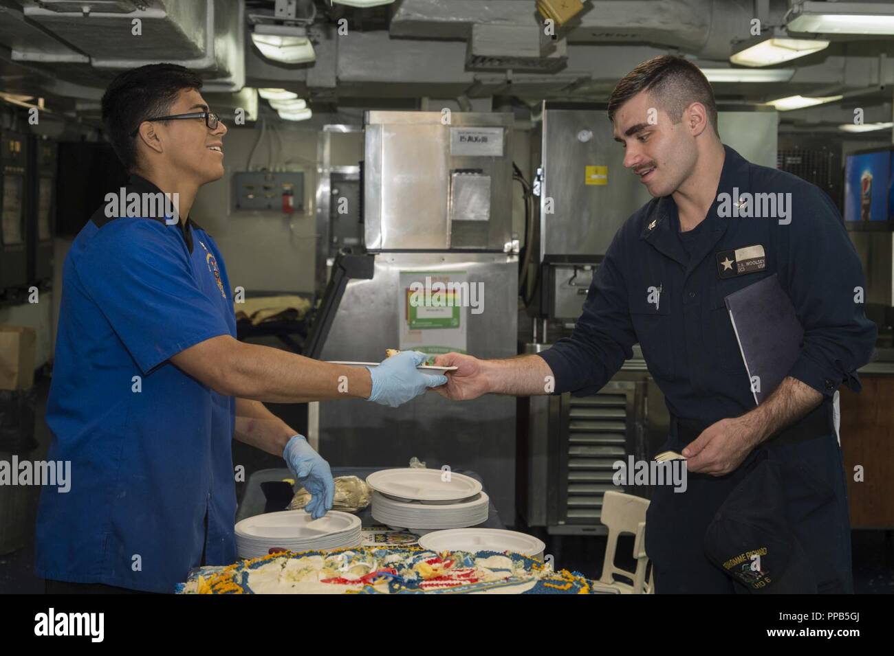 SAN DIEGO (Aug. 16, 2018) Kulinarische Specialist 3. Klasse Max Navarette, Links, aus Ontario, Kalifornien, serviert Geburtstagskuchen zu beschädigen Controlman 3. Klasse Trent Woolsey, von Arlington, Texas, Nach einem Festakt zum 20. Geburtstag der Amphibisches Schiff USS BONHOMME RICHARD (LHD6). 15 August, 1998 beauftragt, Bonhomme Richard ist das dritte Schiff der Namen zu tragen, der sechsten Wasp-Klasse Schiff und der letzte Amphibisches Schiff der Marine im 20. Jahrhundert in Betrieb genommen. Stockfoto