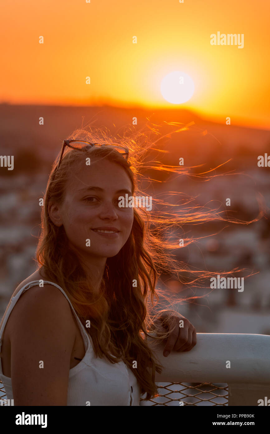 Junge Frau mit Weiß top Lächeln, mit Hintergrundbeleuchtung bei Sonnenuntergang, Plaza de la Encarnacion, hinter den Häusern, Sevilla, Andalusien, Spanien Stockfoto