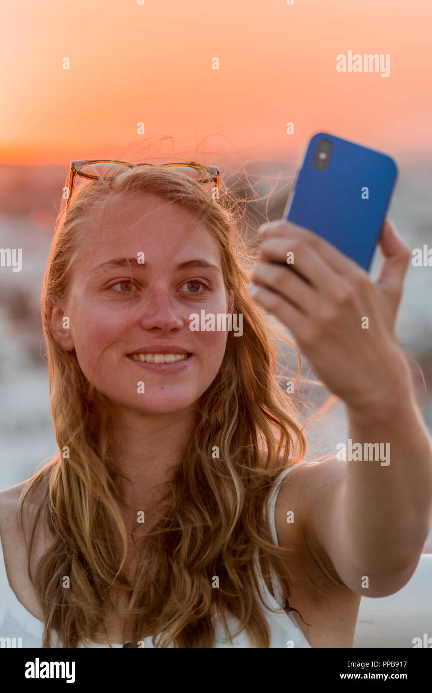 Junge Frau mit Weiß top Fotos selbst mit einem Smartphone, einem selfie, Sonnenuntergang, Plaza de la Encarnacion, Sevilla, Andalusien Stockfoto