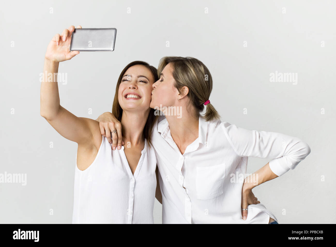 Zwei junge Frau im weißen Hemd Spaß mit selfie machen. Studio shot vor weißem Hintergrund Stockfoto