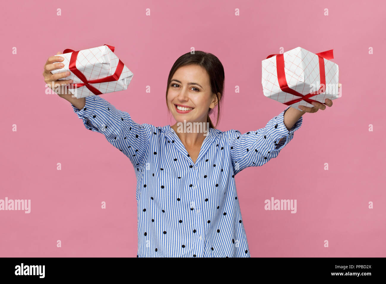 Junge hübsche Frau im blauen Hemd mit einem Lächeln in einem präsentiert. Rosa Hintergrund Stockfoto