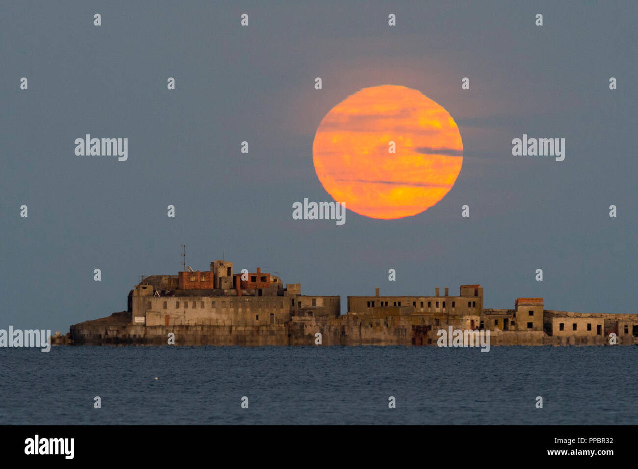 Dorchester, Dorset, Großbritannien. 24. September 2018. UK Wetter. Die Harvest Moon erhebt sich hinter dem historischen des 19. Jahrhunderts Portland Wellenbrecher Fort auf der äußeren Mole Portland Harbour in Dorset. Der jetzt aufgegebenen fort Auch bekannt als Karierten Fort wurde zwischen 1868 und 1878 erbaut und steht unter Denkmalschutz. Foto: Graham Jagd-/Alamy leben Nachrichten Stockfoto