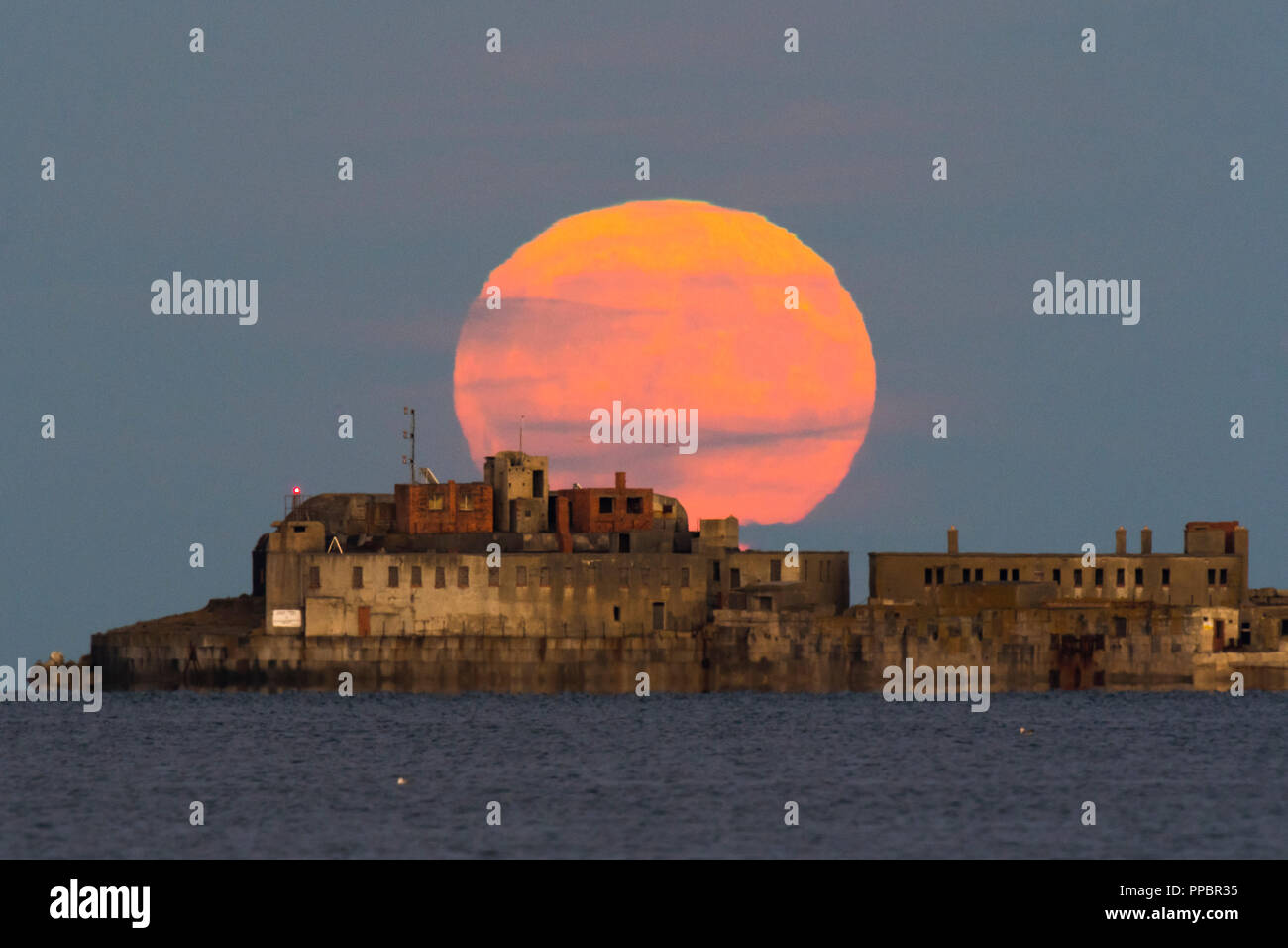 Dorchester, Dorset, Großbritannien. 24. September 2018. UK Wetter. Die Harvest Moon erhebt sich hinter dem historischen des 19. Jahrhunderts Portland Wellenbrecher Fort auf der äußeren Mole Portland Harbour in Dorset. Der jetzt aufgegebenen fort Auch bekannt als Karierten Fort wurde zwischen 1868 und 1878 erbaut und steht unter Denkmalschutz. Foto: Graham Jagd-/Alamy leben Nachrichten Stockfoto