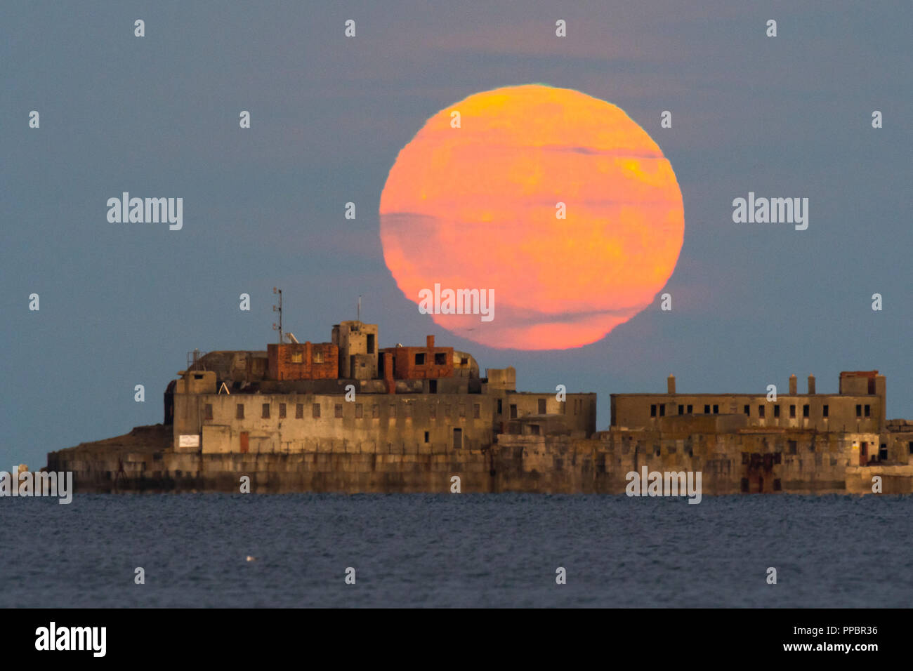 Dorchester, Dorset, Großbritannien. 24. September 2018. UK Wetter. Die Harvest Moon erhebt sich hinter dem historischen des 19. Jahrhunderts Portland Wellenbrecher Fort auf der äußeren Mole Portland Harbour in Dorset. Der jetzt aufgegebenen fort Auch bekannt als Karierten Fort wurde zwischen 1868 und 1878 erbaut und steht unter Denkmalschutz. Foto: Graham Jagd-/Alamy leben Nachrichten Stockfoto