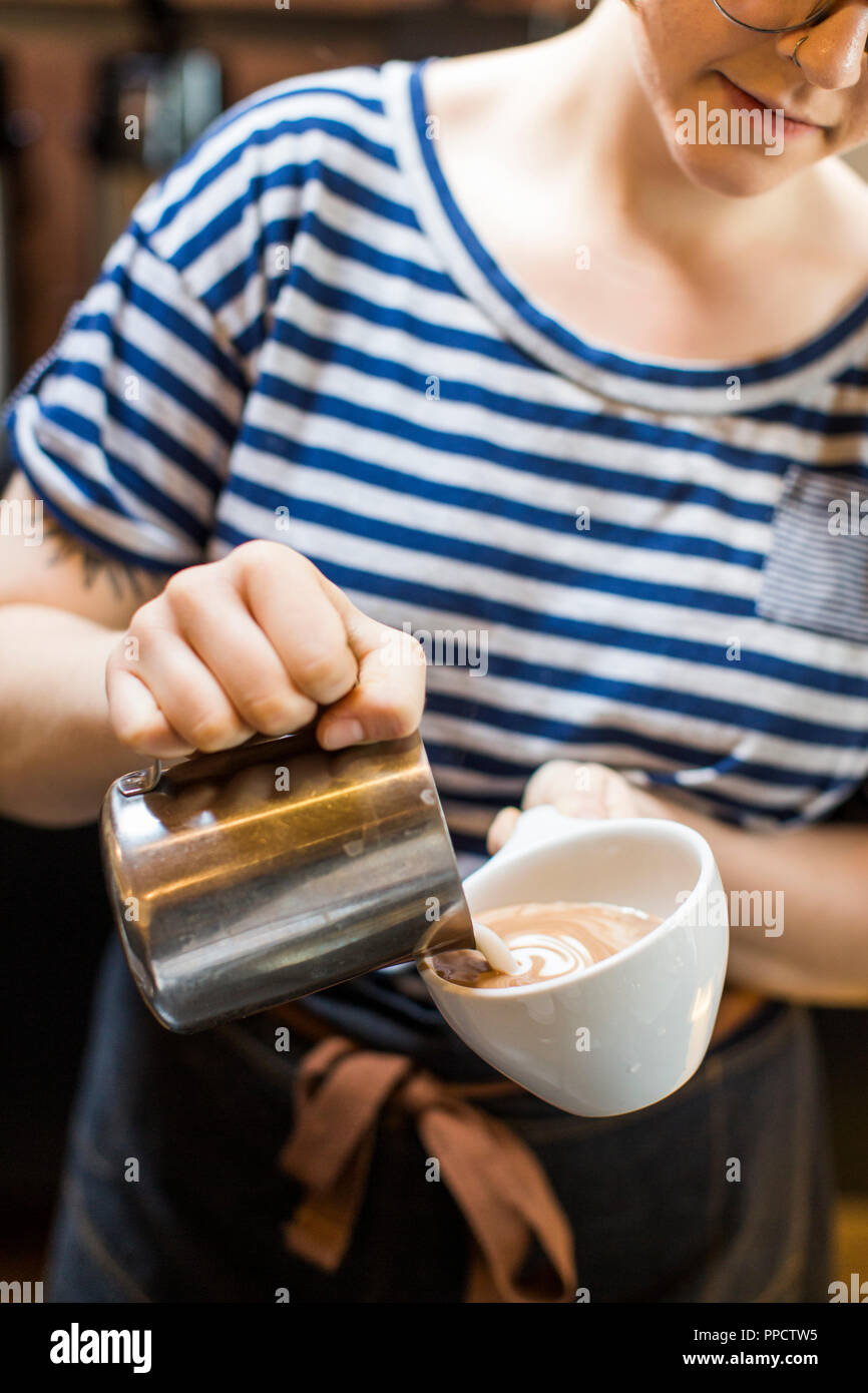 Den mittleren Abschnitt der weiblichen Barista erstellen Latte Art, Seattle, Washington, USA Stockfoto